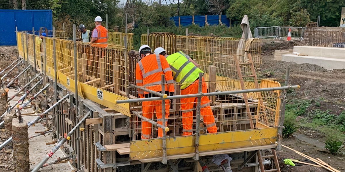 County Civils' team constructing bespoke formwork for a reinforced concrete bridge abutment, with full safety edge protection in place.